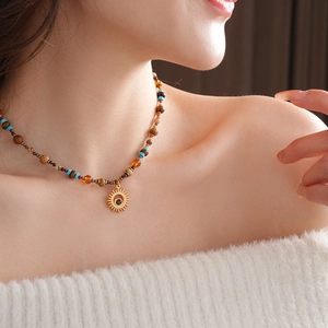 Detail of sun pendant necklace with turquoise beads worn on model neck
