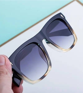 Detail of square gradient sunglasses with purple lenses and golden rivets on frame