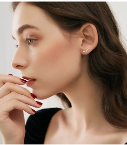 Close-up of five graduated moissanite stones in a silver curved stud earring on model