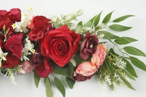Close-up of red and pink artificial rose bouquet with green leaves on white background