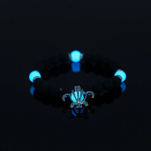 Luminous turtle bracelet with black volcanic stone beads glowing blue on reflective surface