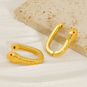 Macro detail of gold snake earrings with red zircon eyes and textured scale patterns