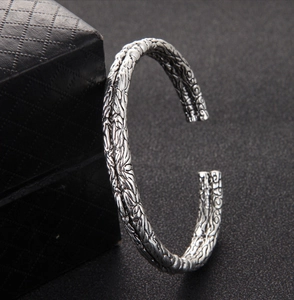 Detailed view of silver open cuff bracelet for men with intricate embossed carvings