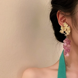 Detail of vintage gold leaf earrings with purple matte grape clusters on a model