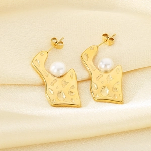 Macro detail of gold irregular geometric earrings with hammered texture and white pearls