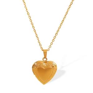 Vintage golden heart locket necklace with delicate floral relief on a white background