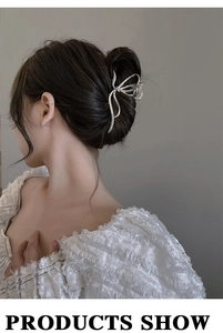 Detail of a silver butterfly hair claw clip worn on a bun hairstyle with metallic finish
