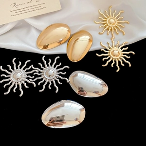 Detailed macro of gold and silver sunburst and teardrop earrings with mirror finish