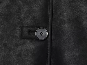 Detailed macro view of black faux suede texture and classic round button on the jacket