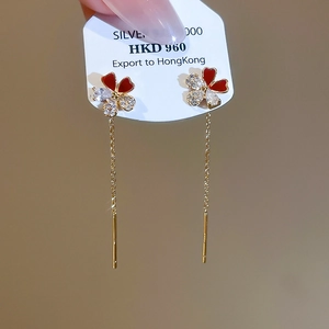 Detail of elegant gold-plated flower drop earrings with red enamel and zircon stones