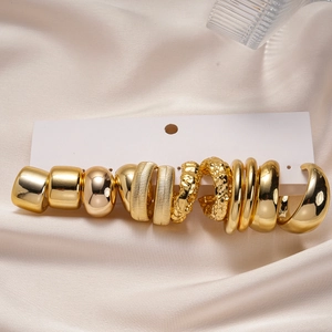 Detail of 12-piece gold geometric earring set with hammered and ribbed textures on silk