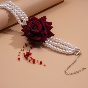 Détail du ras-de-cou à trois rangs de perles avec une rose en velours rouge et franges
