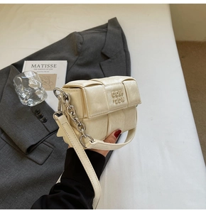 Détail du sac à bandoulière tressé beige avec chaîne en métal et texture cuir luxe