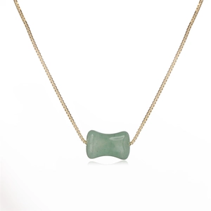 Détail d'un pendentif en pierre verte en forme de bambou sur une chaîne dorée maille