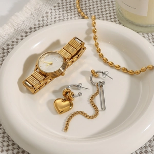 Fashion gold watch and asymmetrical heart tassel earrings set on a white ceramic tray