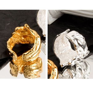 Macro detail of irregular lava texture rings in gold and silver finish on reflective surface