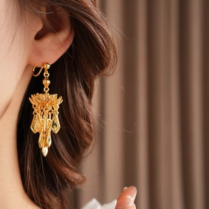 Detail shot of gold-plated lotus leaf tassel earrings featuring vintage floral motifs