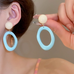 Détail de boucles d'oreilles en résine papillon bleu et blanc avec pendentifs ovales