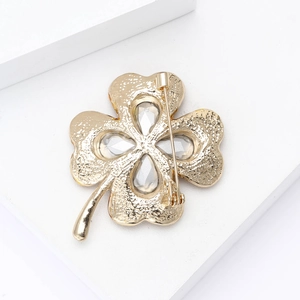 Detail view of the golden metal four-leaf clover brooch back with clear crystal inlay