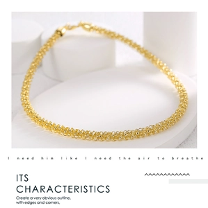 Detail view of a gold-plated woven chain necklace with complex textured link patterns