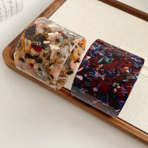 Close-up of wide acetate open cuff bracelets with marbled texture on wooden tray