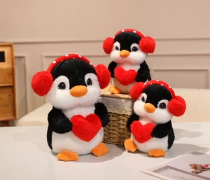 Three sizes of plush penguins with headphones and hearts in a gift arrangement