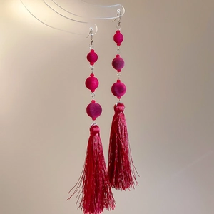Detail of red beaded tassel earrings with soft flocking and elegant metallic hooks
