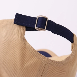 Detail showing the adjustable metal buckle and navy strap of the khaki baseball cap