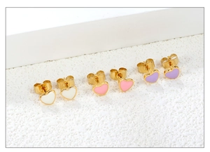 Three pairs of gold-rimmed heart stud earrings in white, pink, and purple enamel