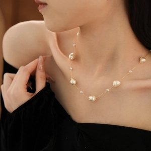 Close-up of a gold-plated baroque pearl necklace worn on a woman's collarbone