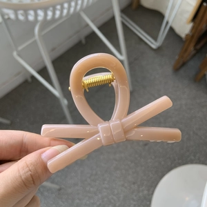 Close-up of a matte peach bow hair claw clip with a durable gold spring mechanism