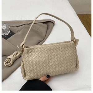 Détail de la texture tressée du sac beige avec finitions dorées et bandoulière