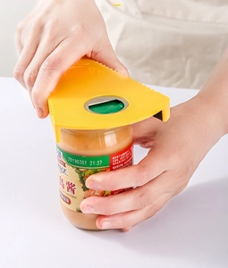 Détail d'un ouvre-boîte jaune antidérapant dévissant un couvercle dans une cuisine
