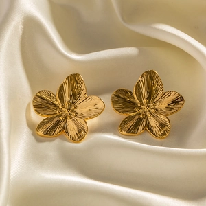 Matte gold four-petal flower earrings with brushed metal texture on white silk background