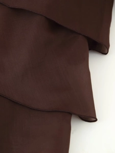 Dettaglio macro di balze in chiffon marrone scuro con cuciture sui bordi rifinite