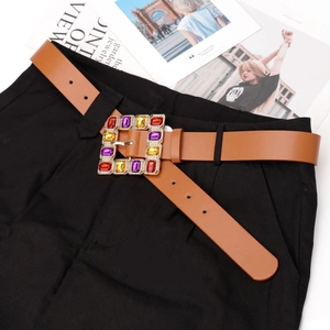 Brown leather belt with gold square buckle and colorful rhinestones on black pants