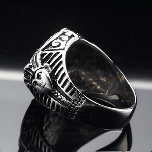 Macro shot of retro Pharaoh tutankhamun stainless steel ring on a black reflective surface