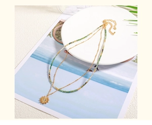 Detail of layered gold sun pendant necklace with green natural stone handmade beads