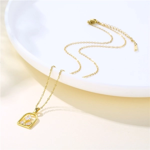 Elegant gold stainless steel necklace with crystal rose pendant on white ceramic tray