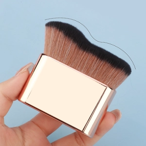 Macro shot of wavy-edged foundation brush head with rose gold handle and gradient bristles