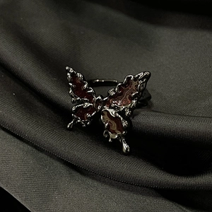 Detail of gothic butterfly ring with melting metal texture and dark red enamel finish