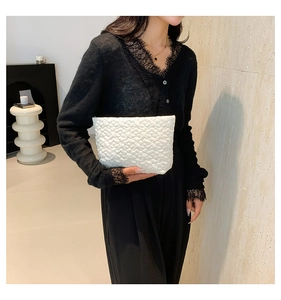 Detailed close-up of white pleated floral texture fabric on a minimalist clutch bag