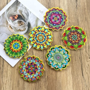 Detailed view of colorful mandala coasters with gold edges on a wooden table surface