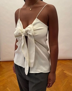 Close-up of off-white satin camisole featuring a large bow tie and thin straps