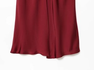 Detailed close-up of burgundy satin dress hem showing smooth silk texture and fine stitching