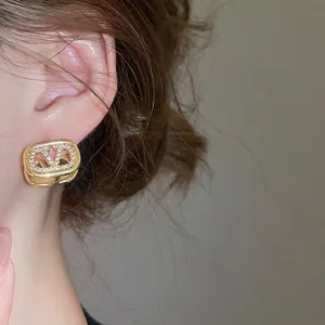 Elegant 18k gold plated V-logo earrings with sparkling cubic zirconia on a model