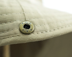 Macro detail of breathable ripstop fabric and star-engraved metal eyelet on sun hat