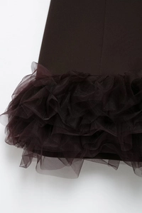 Detailed close-up of dark brown layered mesh ruffles and textured fabric on the dress hem