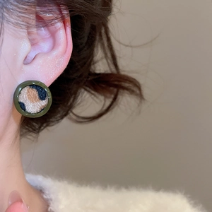 Gros plan d'une boucle d'oreille ronde léopard avec bordure en résine vert foncé sur le mannequin