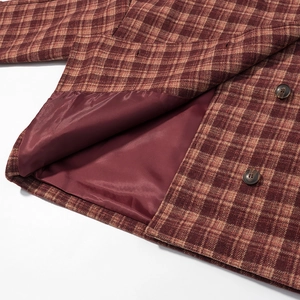 Détail du manteau à carreaux rouge-brun montrant la doublure lisse et le bouton en écaille